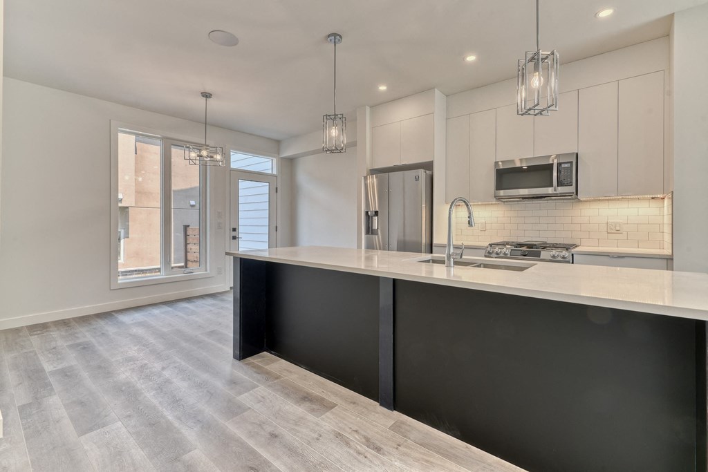 A modern kitchen with a black countertop and a microwave above it.