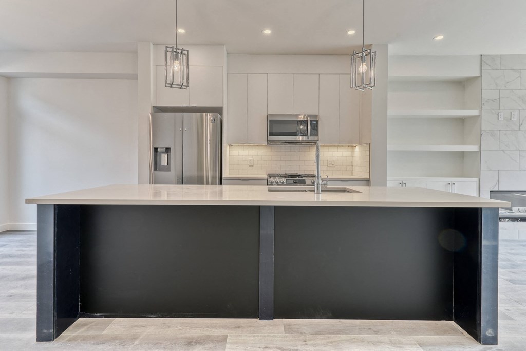 A modern kitchen with a large island and a refrigerator.