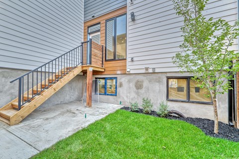A house with a wooden deck and a tree in front.