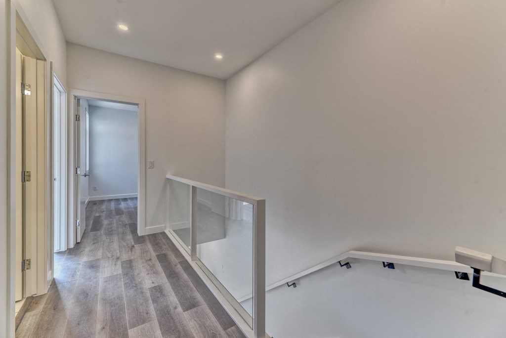A hallway with a wooden floor and white walls.
