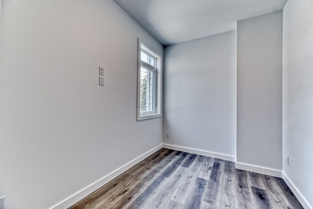 A room with a window and wooden flooring.