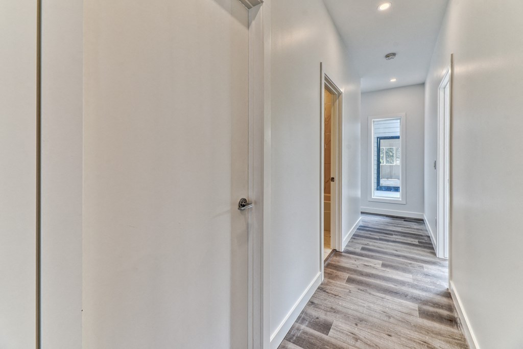 A long hallway with a door on the left and a window on the right.