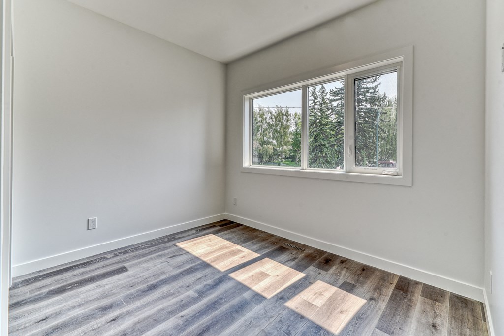 A room with a window and a wooden floor.