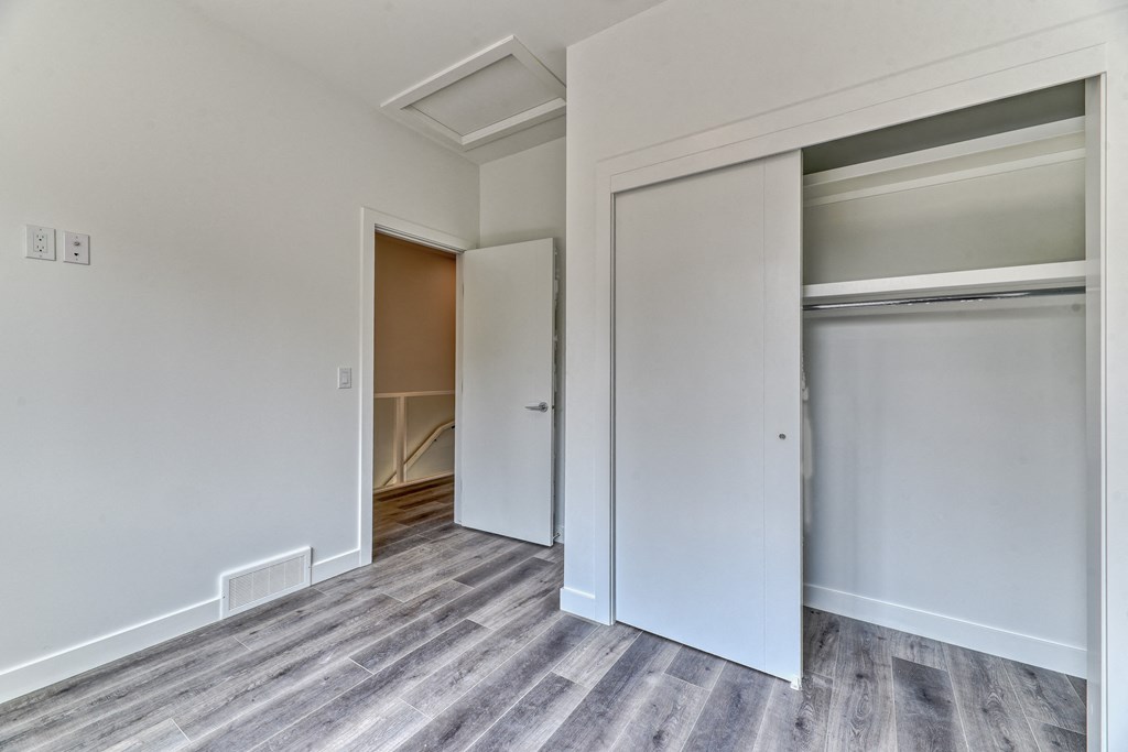 A room with a white door and a grey carpet.