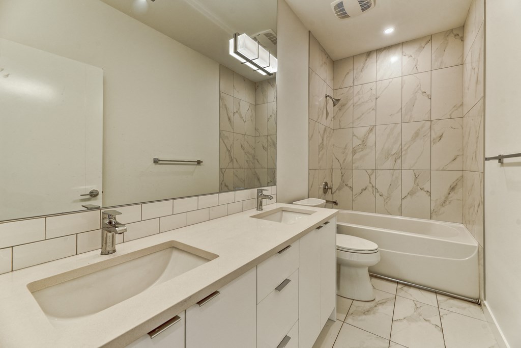 A white bathroom with a marble wall and a white bathtub.