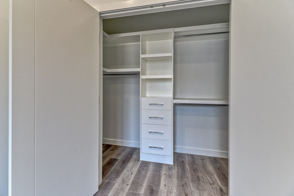 A walk-in closet with white shelves and drawers.