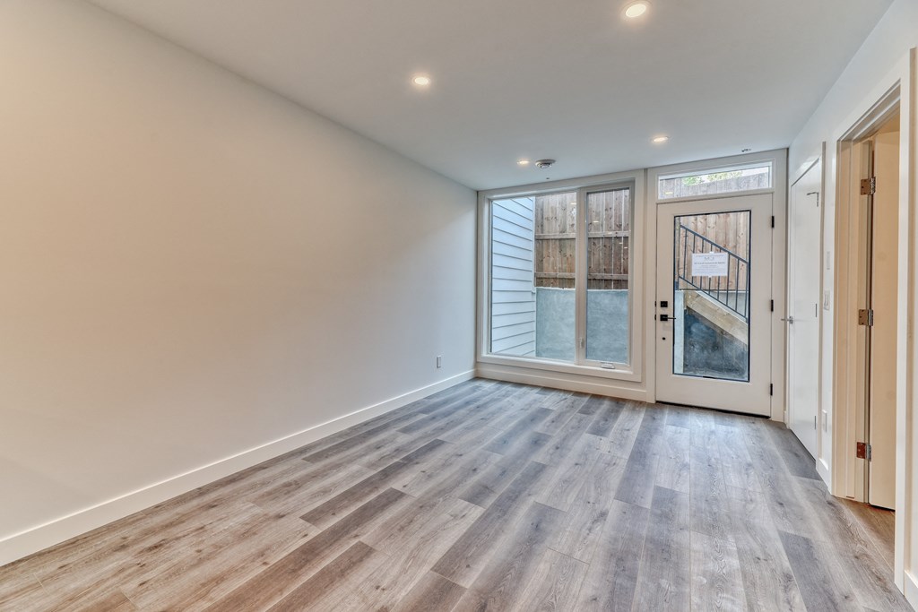 A room with a wooden floor and a glass door leading outside.
