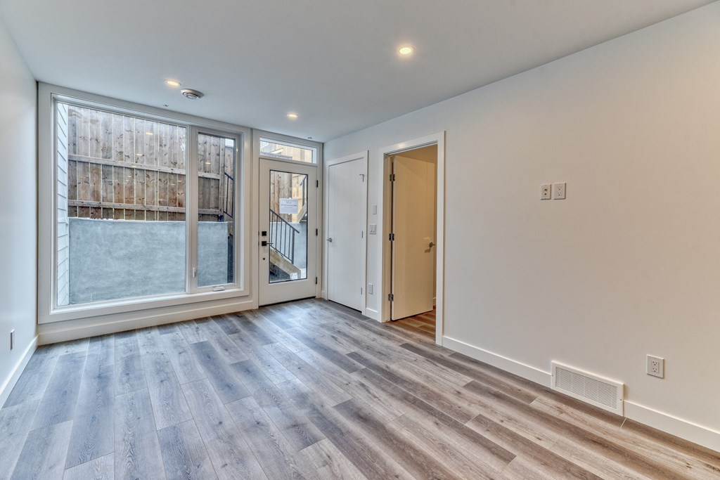 A room with a wooden floor and a glass door leading to a balcony.
