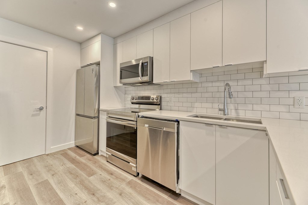 A kitchen with white cabinets and a wooden floor.
