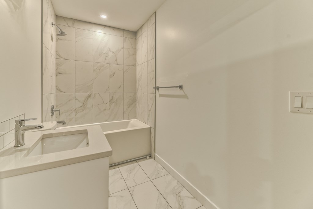 A white bathroom with a sink, tub, and shower.