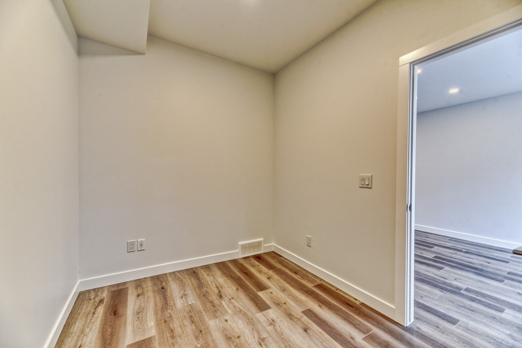 A room with wooden flooring and white walls.
