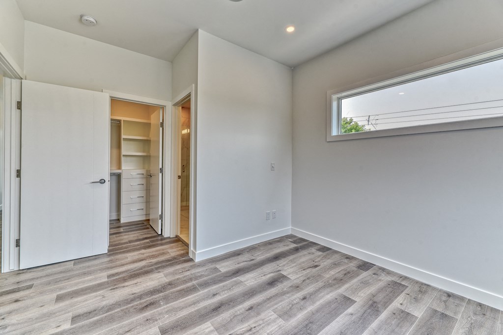 A room with a white door and a window with a view of trees outside.