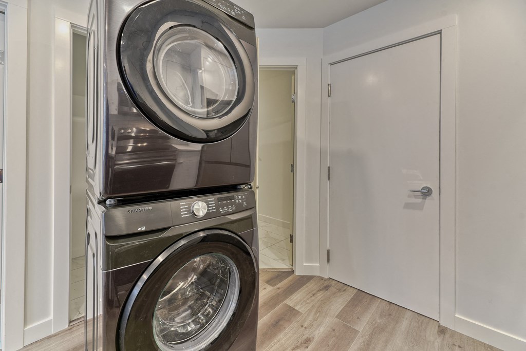 A stack of two front loading washing machines in a laundry room.