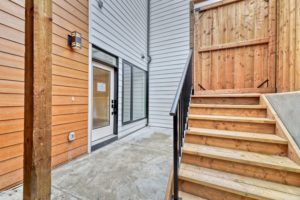 A wooden staircase leads to a glass door entrance.