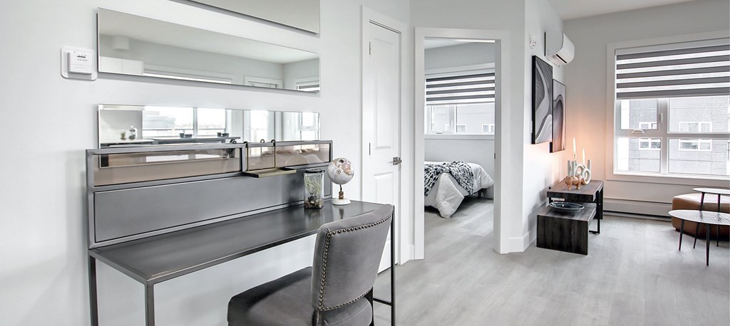 A modern bedroom with a large mirror above a vanity table.