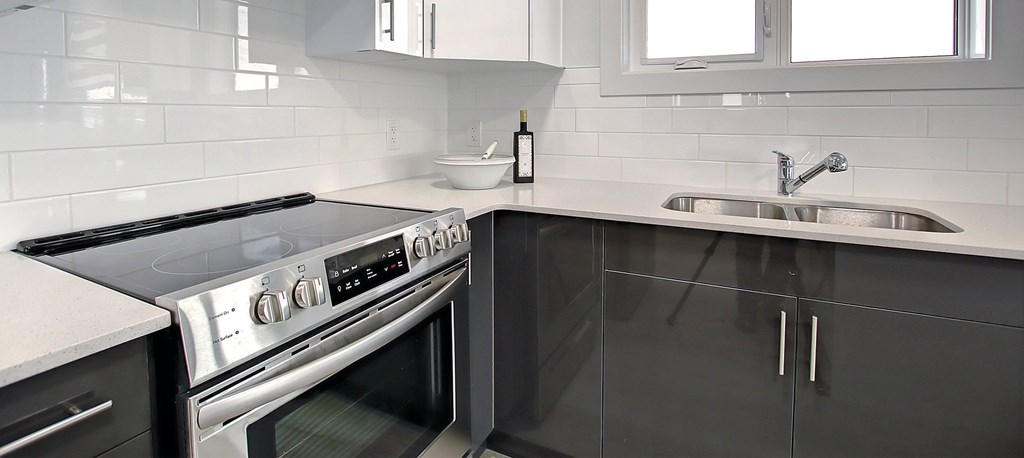 A modern kitchen with a stove top oven and a sink.