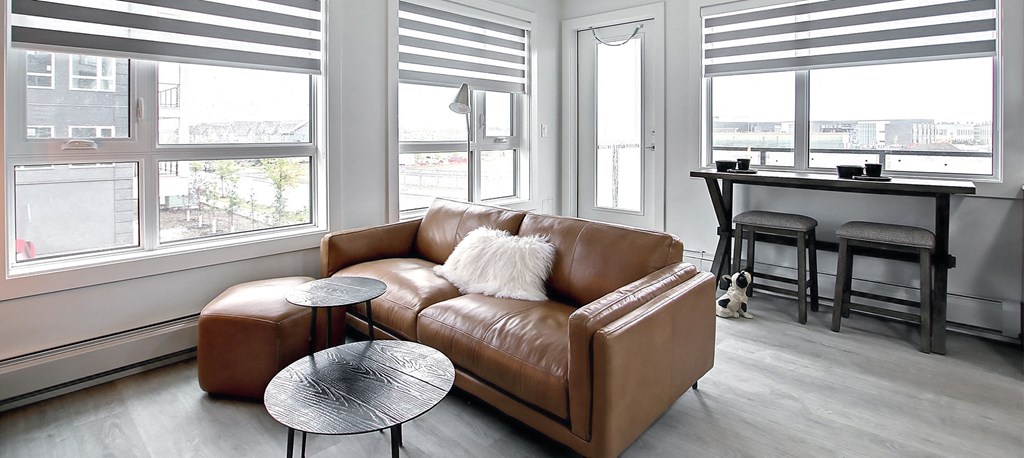 A brown leather couch with a round table in front of it.