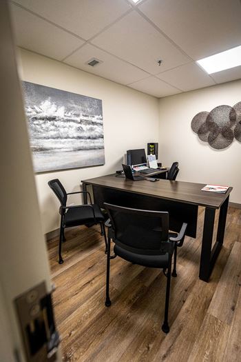 an office with a desk and chairs and a painting on the wall