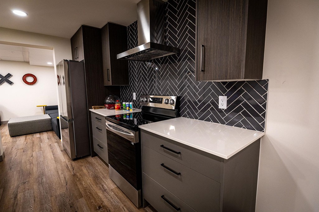 a kitchen with black cabinets and a white counter top and a refrigerator