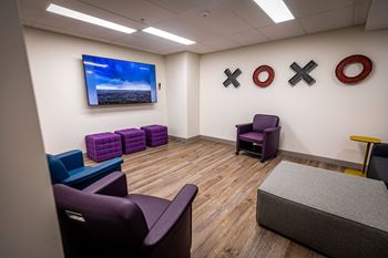 a waiting room with purple chairs and a tv