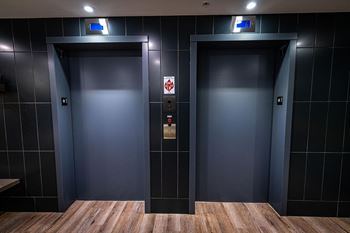 two blue elevators in a lobby with wood floors and tile walls