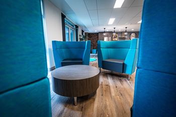a lounge area with blue chairs and a coffee table