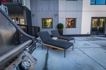 two lounge chairs on the sidewalk in front of a building
