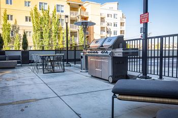 a barbecue grill on a patio with a table and chairs