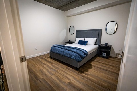 a bedroom with a bed in a room with wooden floors