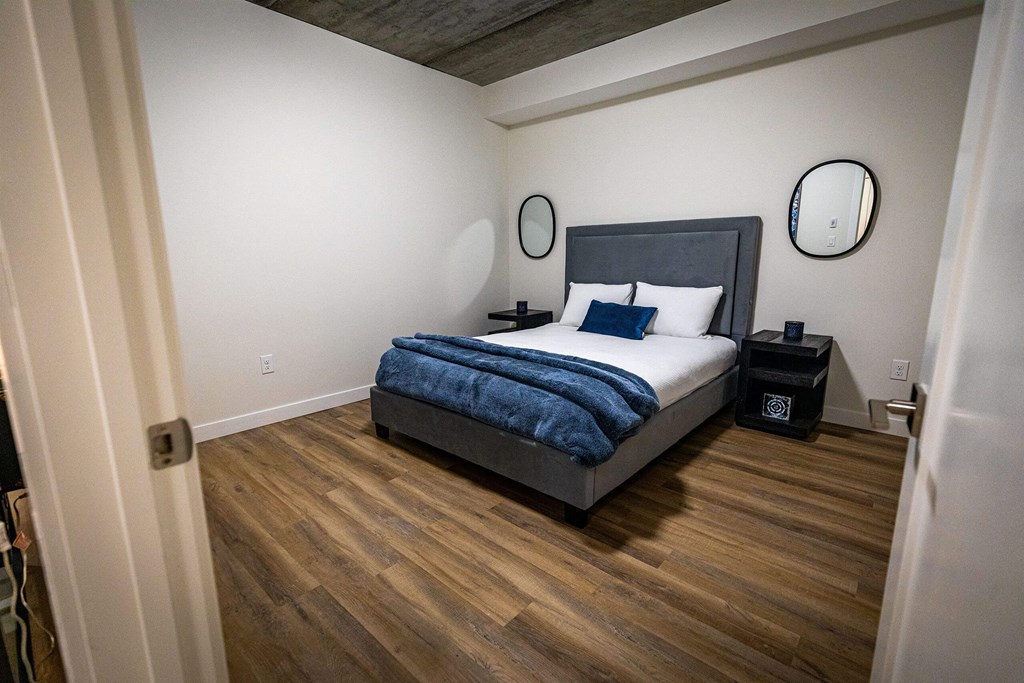 a bedroom with a bed in a room with wooden floors