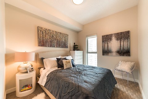 A bedroom with a bed, nightstand, and two pictures on the wall.