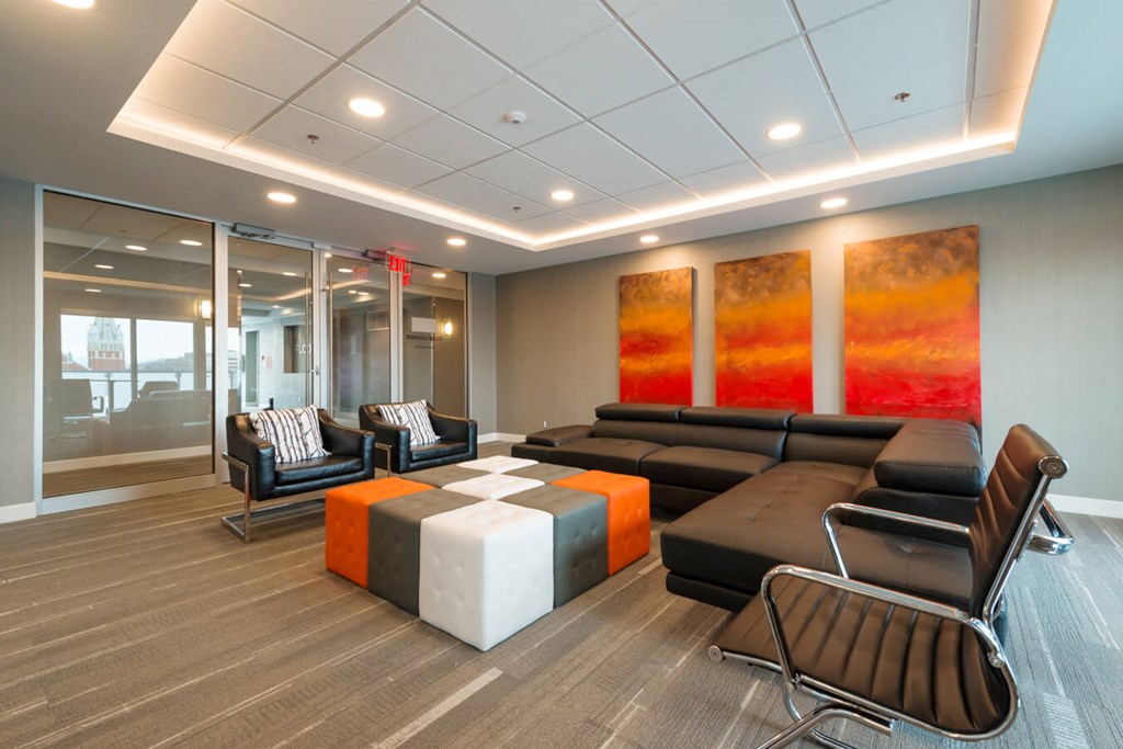 A modern living room with a black leather couch and a glass wall.