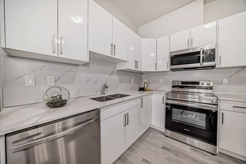 A modern kitchen with white cabinets and stainless steel appliances.