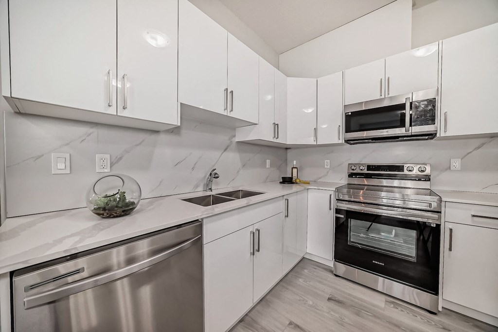 an all white kitchen with stainless steel appliances and white cabinets