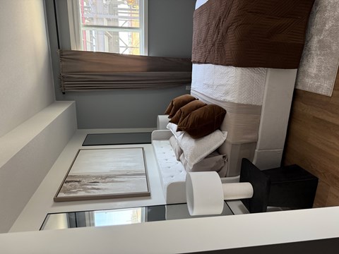 A room with a bed, a table, and a window with blinds.