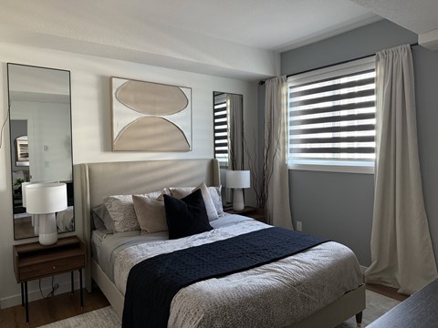 A bedroom with a bed, nightstand, and a painting on the wall.