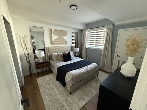 A bedroom with a bed, nightstand, and lamp.