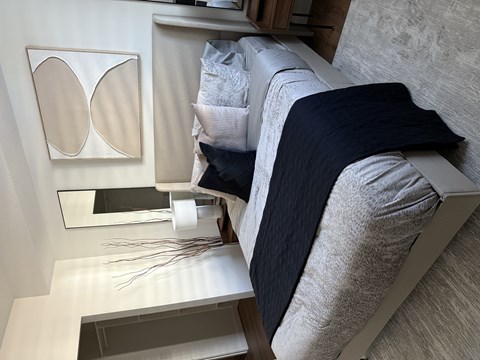 A modern bedroom with a bed, nightstand, and decorative mirror.