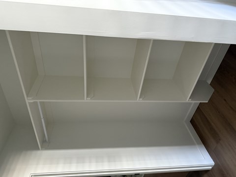 A white shelving unit with a white ceiling and a white floor.