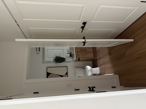 A white bathroom with a mirror and a toilet paper holder.