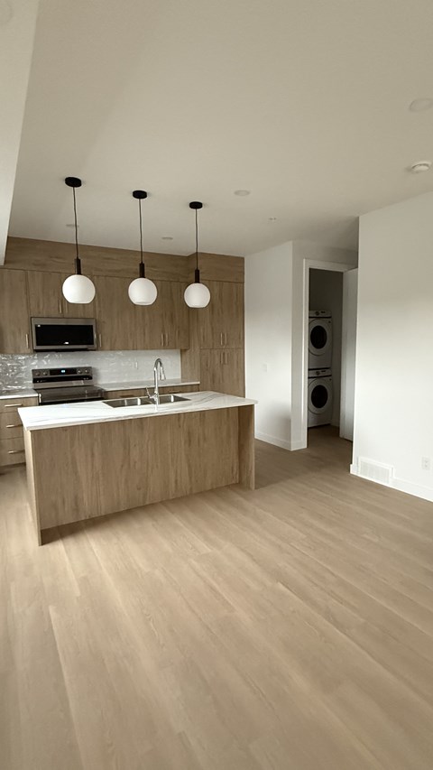 A modern kitchen with a wooden island and pendant lights.
