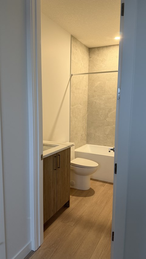 A white toilet sits in a bathroom next to a white bathtub.