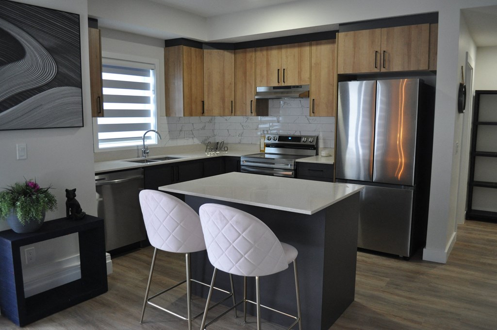 A kitchen with a white countertop and a refrigerator at The Laurent at Laurel Apartments, Edmonton, AB, T6T 2T5