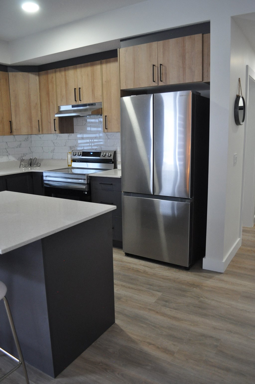 A modern kitchen with a stainless steel refrigerator and wooden cabinets at The Laurent at Laurel Apartments, Alberta