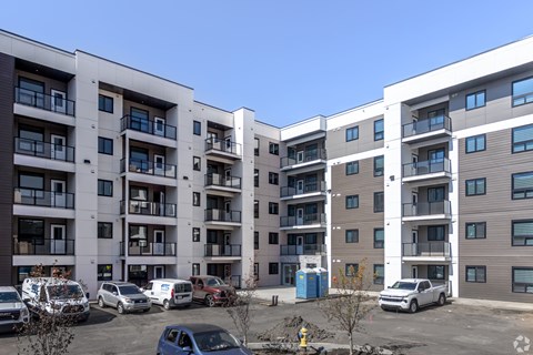 A parking lot with cars and apartment buildings in the background.