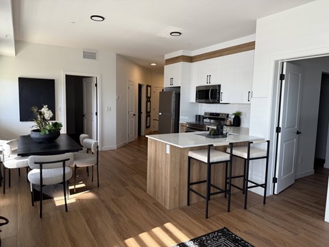 A kitchen with a table and chairs in the foreground and a refrigerator in the background.