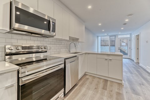 A modern kitchen with stainless steel appliances and white cabinetry.