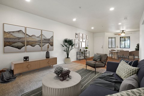 A living room with a grey couch, a coffee table, and a painting on the wall.