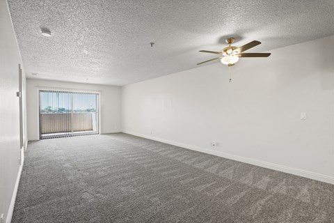 A spacious room with a ceiling fan and carpeted floor.