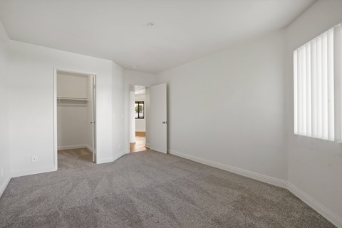 A spacious empty room with carpeted floor and white walls.